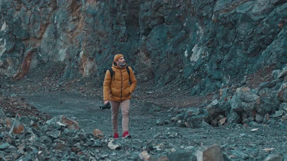 Professional Photographer with a Camera in His Hands Walking in a Gorge and Looking for an Unusual