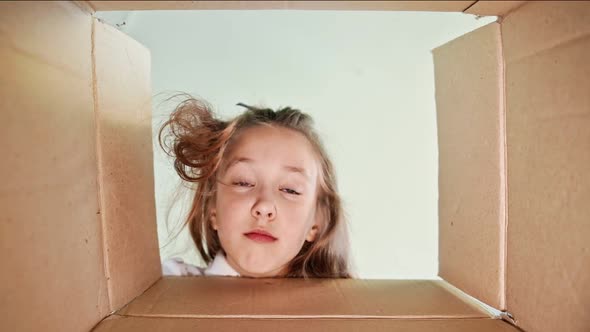 Serious Child Delighted with a Surprise Opens a Box with Gifts