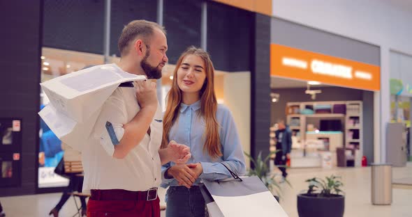 Beautiful Young Couple Standing and Discussing Something in the Mall