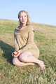 Full length of young woman having apple on grassy hill - PhotoDune Item for Sale