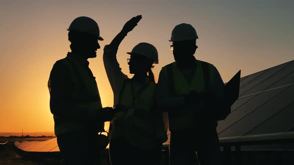 Sunset with Team of Engineers Arguing Near Solar Panels