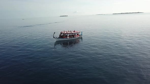 Spiral drone shot of a boat with people seating in yoga positions on the roof top. 4K