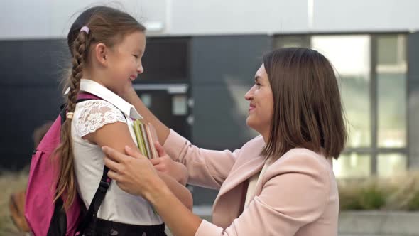 Young Woman Gently Hugs a Girl with Pigtails 67 Years Old