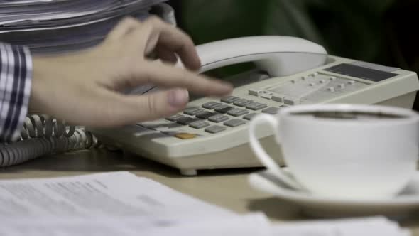 Office worker uses a landline phone to answer incoming calls and dialing a number to make a call