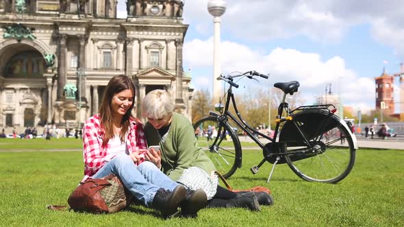 Two women relaxing in Berlin with the Cathedral on background