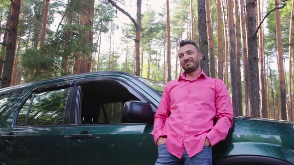 A Happy Businessman Stands Leaning on a Car Resting Admiring the Nature