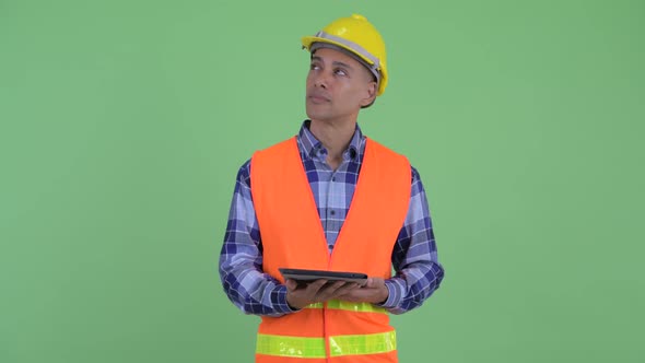 Happy Multi Ethnic Man Construction Worker Thinking While Using Digital Tablet