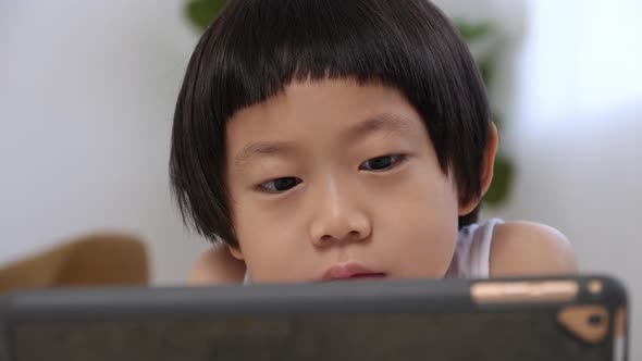 Cute little boy using tablet computer at home.