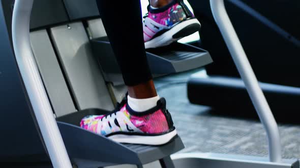 Low-section of fit woman exercising on cross trainer