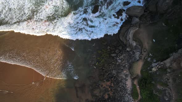 Aerial view of waves crashing into a rocky shoreline in Geriba Beach, Buzios, Brazil