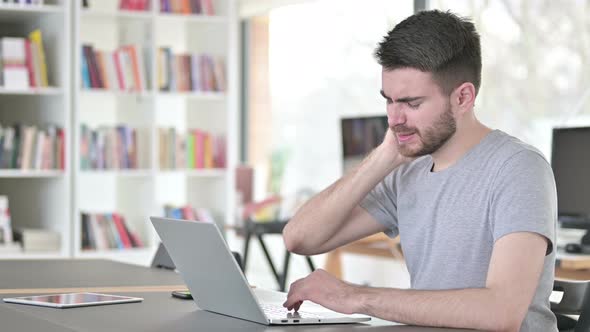 Young Man with Neck Pain Using Laptop in Office