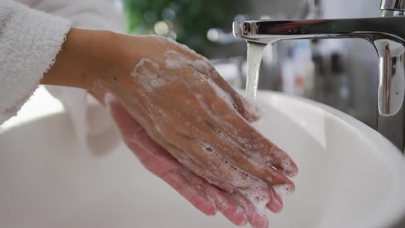 Mid section of mixed race woman washing her hands in bathroom