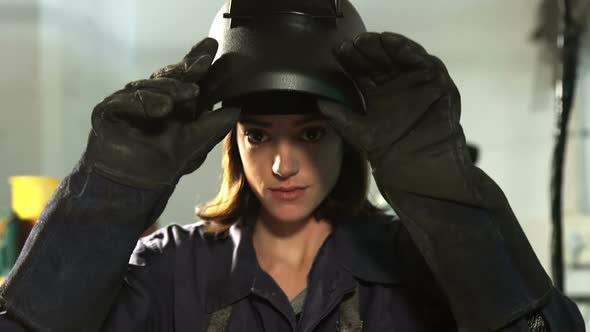 Female welder removing helmet