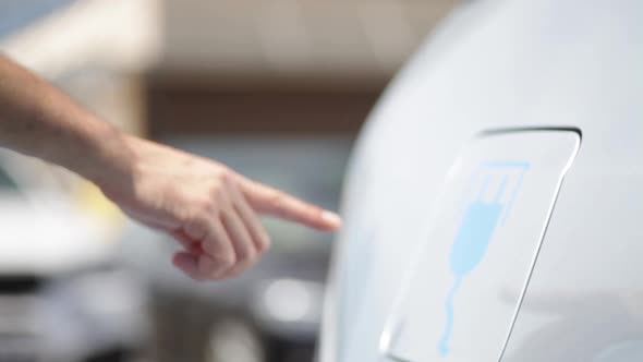 Hand opening the lid of an electrical car, for charging