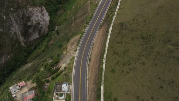 Aerial view that shows an empty highway along a hillside with a bright yellow stripe in the middle