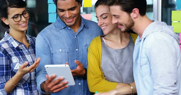 Smiling executives discussing over digital tablet during meeting