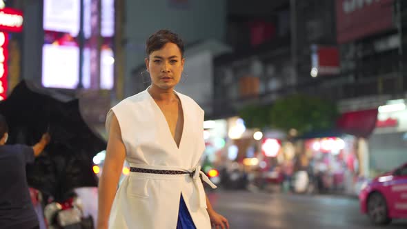 4K Confidence Asian lgbtq guy wearing woman clothes walking down city street at night