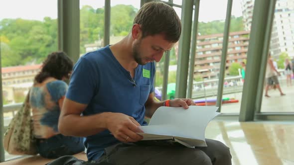 Male Student Preparing for Test, Sitting at University Hall and Reading Notes