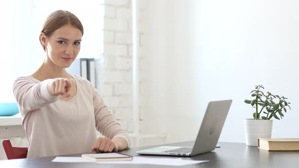 Woman Pointing toward Camera in Office