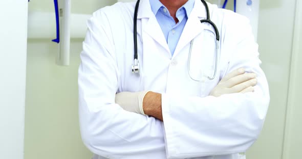 Portrait of smiling dentist standing with arms crossed