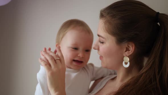 Mother in a White Coat Holds Her Little Blonde Daughter Against the Wall