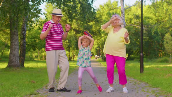 Granddaughter Together with Senior Grandmother Grandfather Listening to Music Dancing Crazy in Park