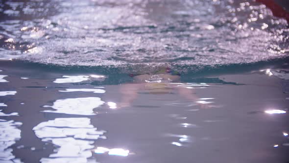 A Man Swimmer in Golden Cap Swimming Underwater in the Pool