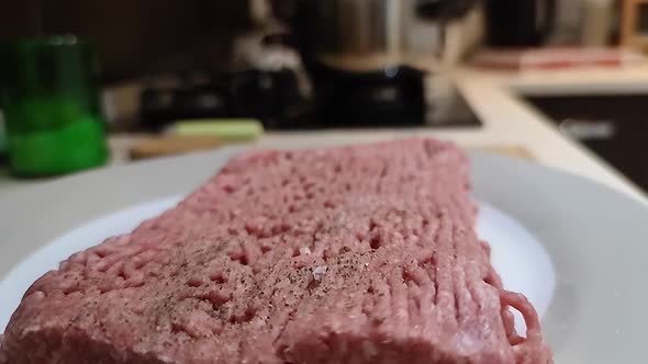 Ground Meat With Pepper And Salt On White Plate Ready For Cooking In Kitchen. - close up, dolly