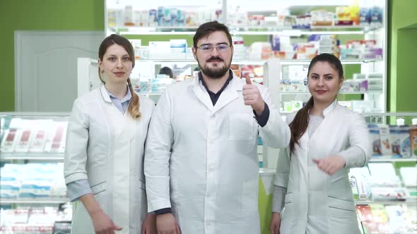 Three Young Caucasian Pharmacists Showing Thumbs Up To the Camera and Smiling. Highly Professional