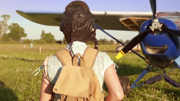 Young Adventurous Woman Pilot Walking To Old Airplane at Summer Sunset, Freedom and Feminism Concept