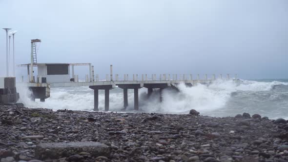 Storm waves crash against old reinforced concrete pillars on the beach