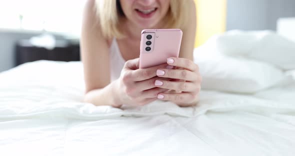 Woman Texting on Smartphone While Lying in Bed at Home