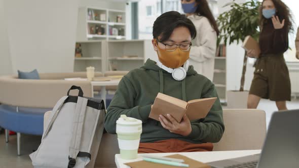 Male Student in Mask Reading Book