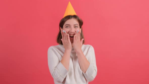 Excited Young Woman in Birthday Hat Posing Isolated on Red Background