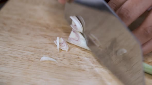 Cutting Lemongrass into small Slices with Knife on Wooden Cutting Board - Close Up