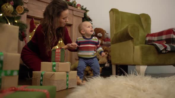 Cute Joyful Cheerful Mother and Baby Spend Their Leisure Time Next To the Christmas Tree at Home