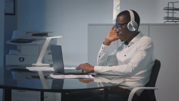 Dolly Shot of Happy African Businessman Listening to Music in Headphones Working in Office