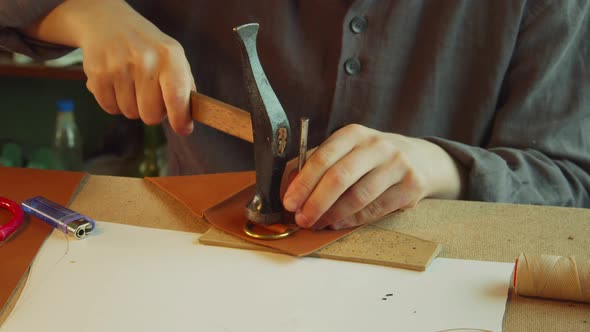 Close-up Slowmotion Without a Face a Tailor with a Core and a Hammer Makes Holes in a Product Made