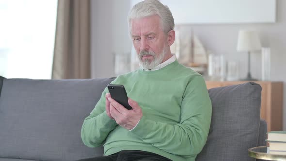 Attractive Old Man Using Smartphone at Home