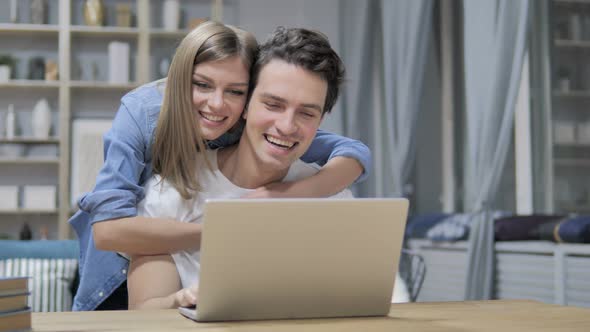 Casual Happy Young Couple Using Laptop at Home