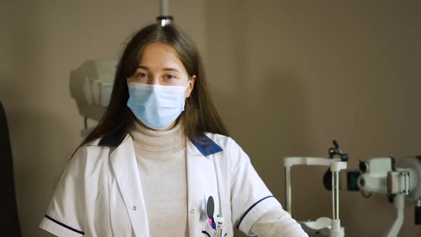 Dolly In: Cute Young Doctor in Medical Face Mask Looks at You