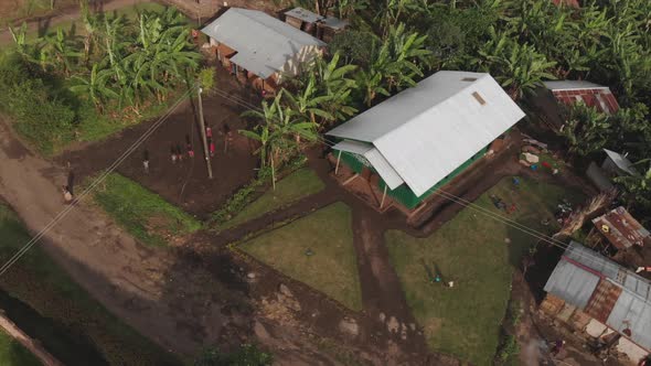 Aerial drone shot of children running away and playing together on a village in Uganda, Africa.