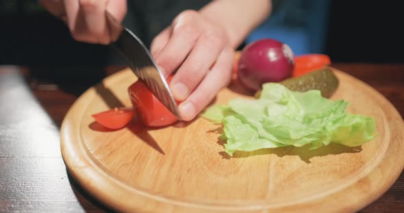 The Cook Slices Tomato By Sharp Knife on the Wooden Board. Making of Vegetable Salad, Vegetarian