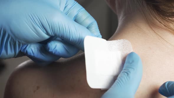 Doctor Sticks a Bandaid Patch on the Wound on the Patient's Back