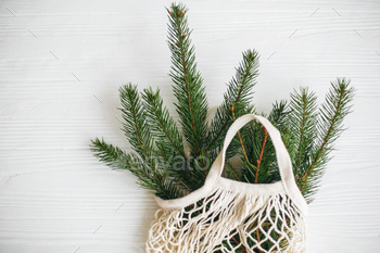 te holidays. Sustainable lifestyle. Reusable cotton bag with green spruce branches on white rustic background.