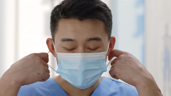 Close Up View of Asian Doctor Taking Off Medical Protective Mask Looking to Camera