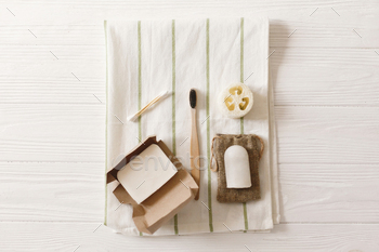  eco bamboo toothbrush, crystal deodorant,coconut soap,ear sticks,luffa on towel, flat lay.  plastic free items for  hygiene