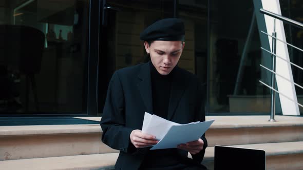 Focused Businessman Reading Business Papers on an Urban Street. Man Working on City Stairs