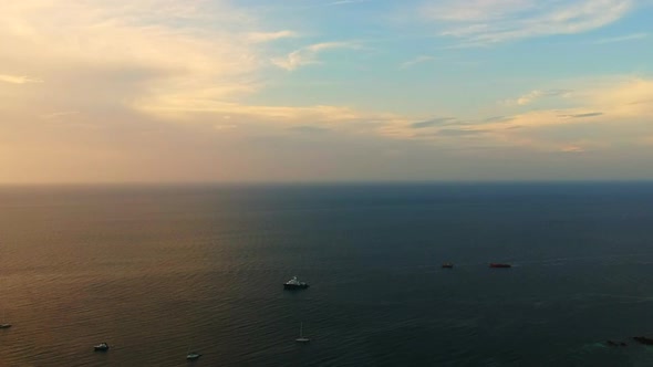 Aerial shot of an Ocean with a speed boat, long tail boat next to it and a cloudy blue sky in the ba