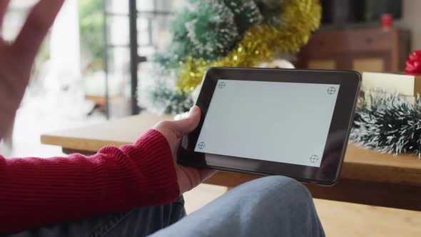 Happy albino african american man wearing santa hat using tablet with copy space at christmas